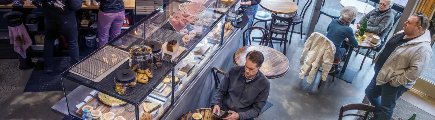 a busy morning in a cafe. people sitting at tables and standing waiting for coffee.