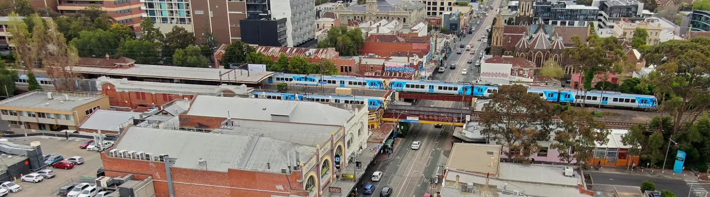 an overhead photo of a suburb with a main street and elevated train lines