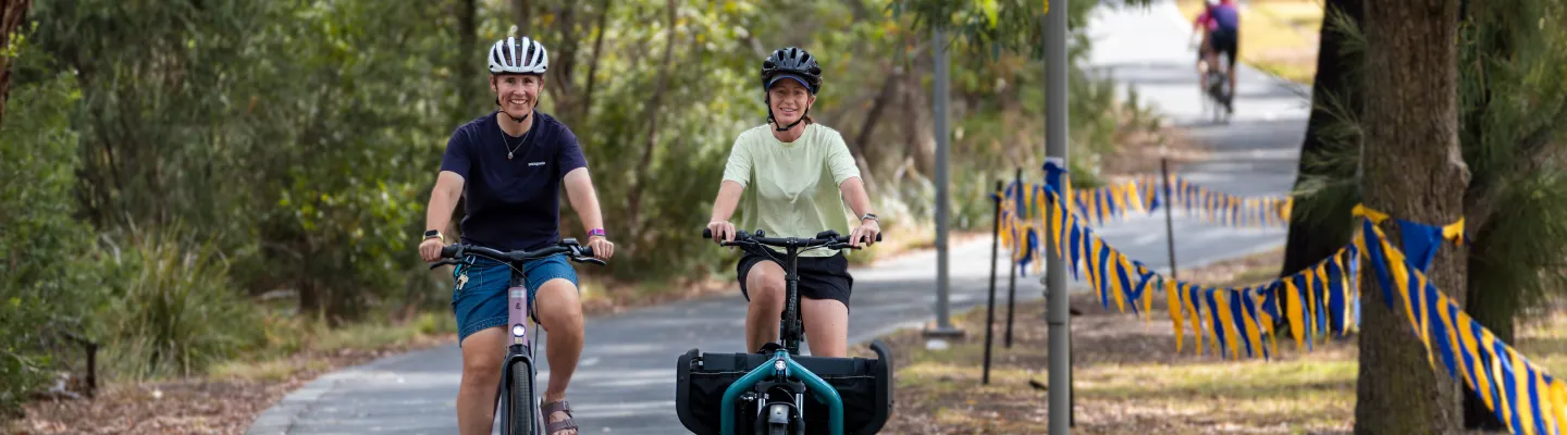 Two people riding bikes on a sunny day along a bike path.