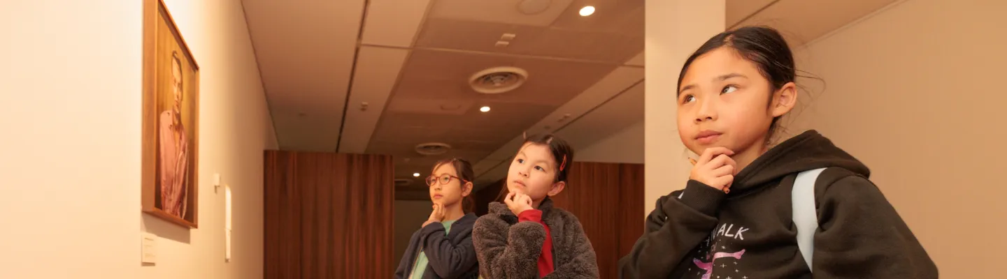 Three young people looking thoughtfully at artworks in a gallery.