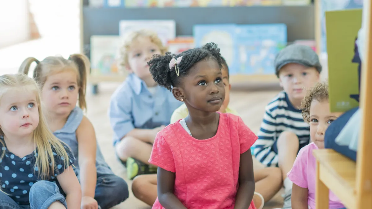 A group of children listening to a book being read by an adult