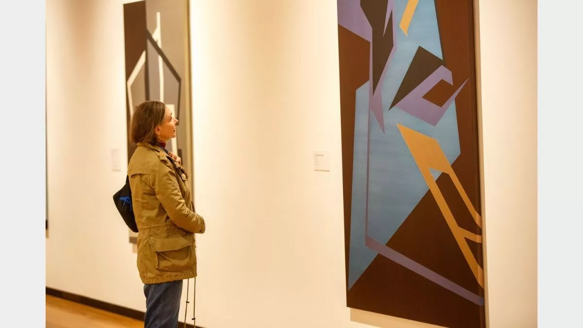 Visitor to 'Light Gestures' looking at painting on the wall.