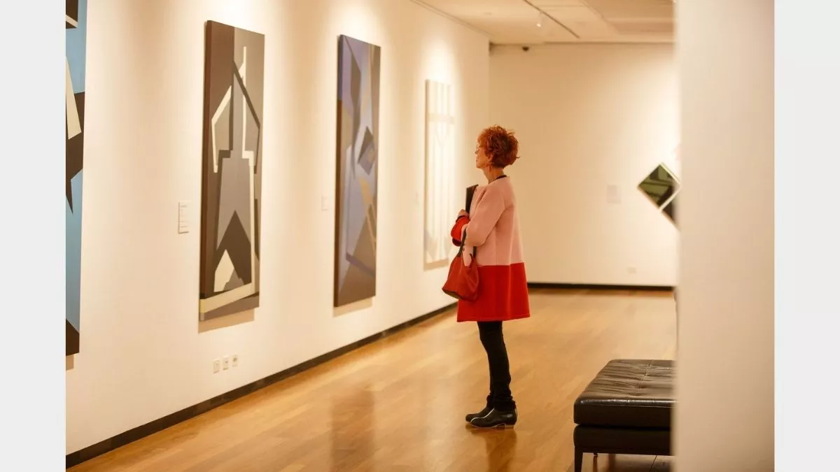 Visitor to 'Light Gestures' looking at painting on the wall.