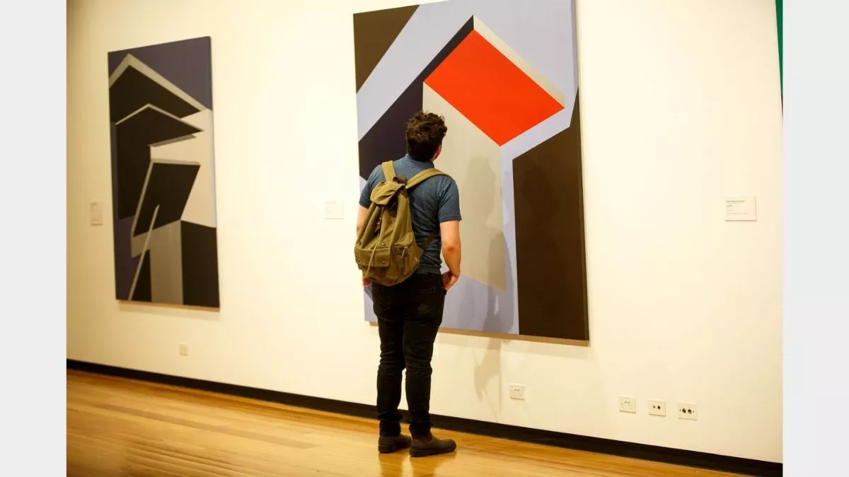 Visitor to 'Light Gestures' looking at painting on the wall.