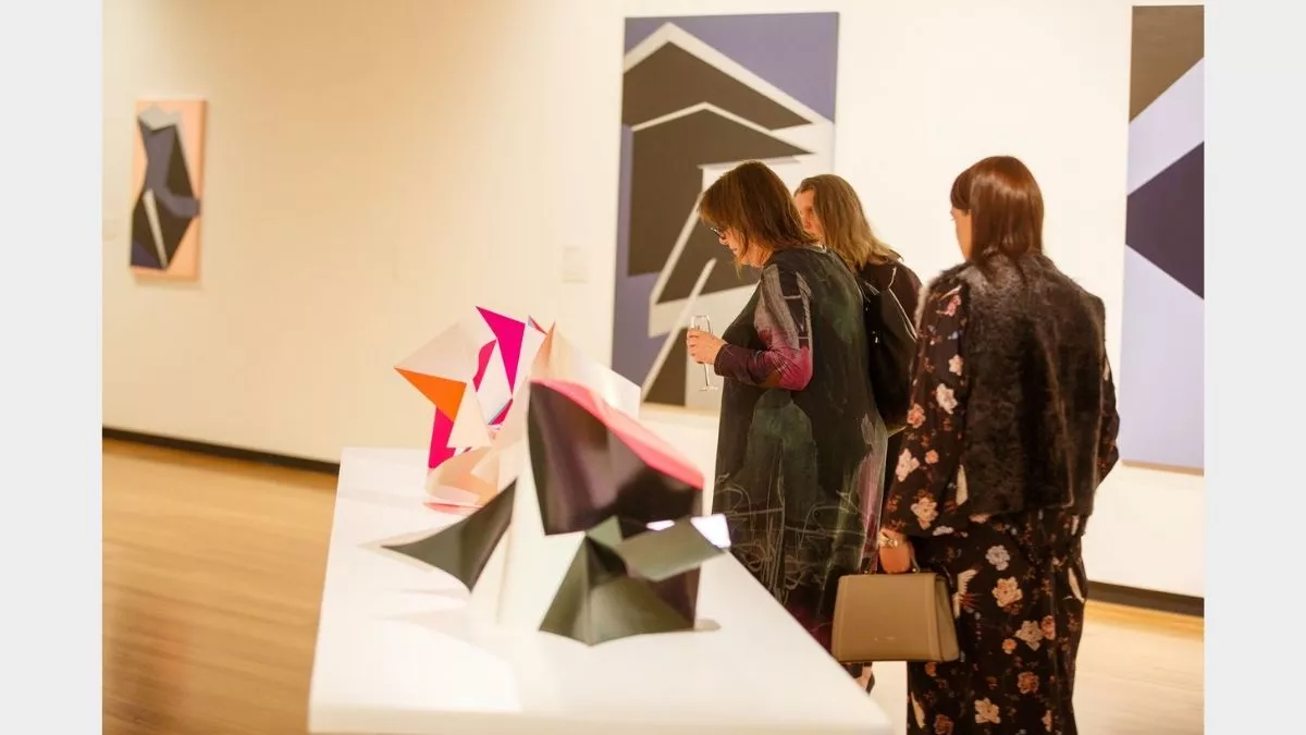 Visitors to 'Light Gestures' looking at sculptures on a table.