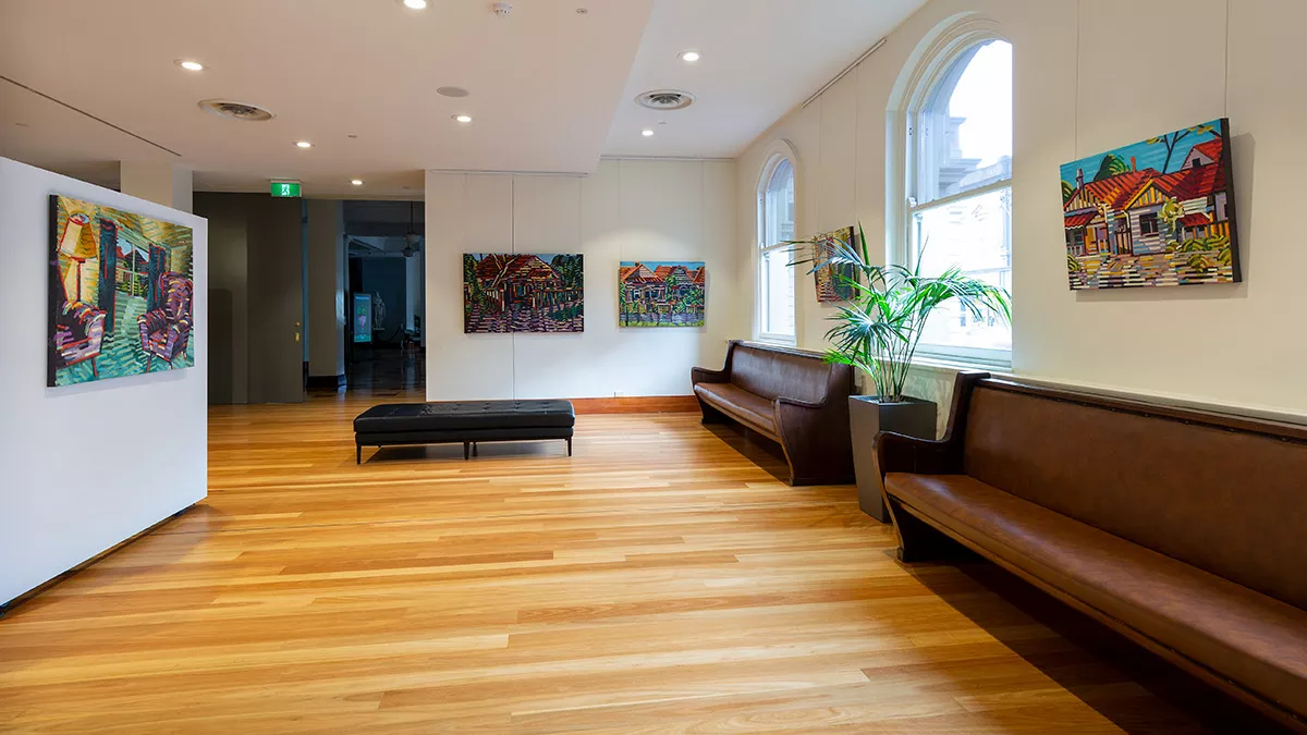 On the left, a section of movable wall. Along the other walls are seats, windows and paintings.