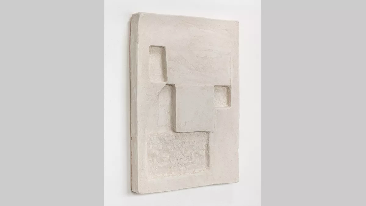 A flat rectangular form on a wall, with geometric shapes indented into it.