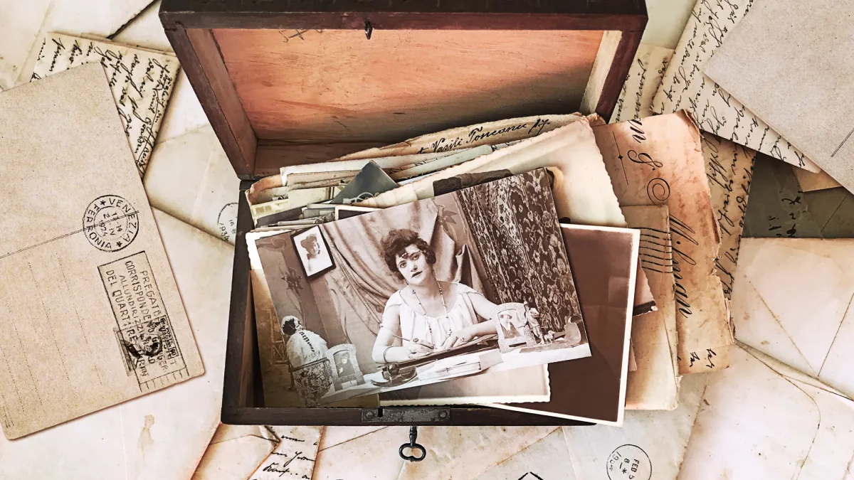 Old photos in a box resting on a background of vintage postcards