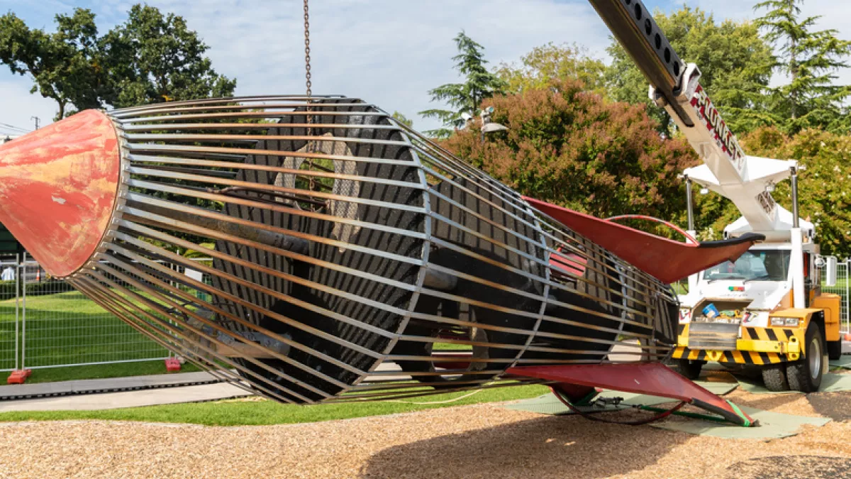A large play rocket is removed from the playground by a crane