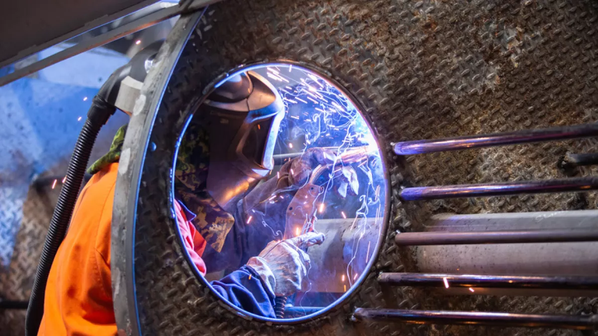 View through a playground rocket window to a worker welding inside