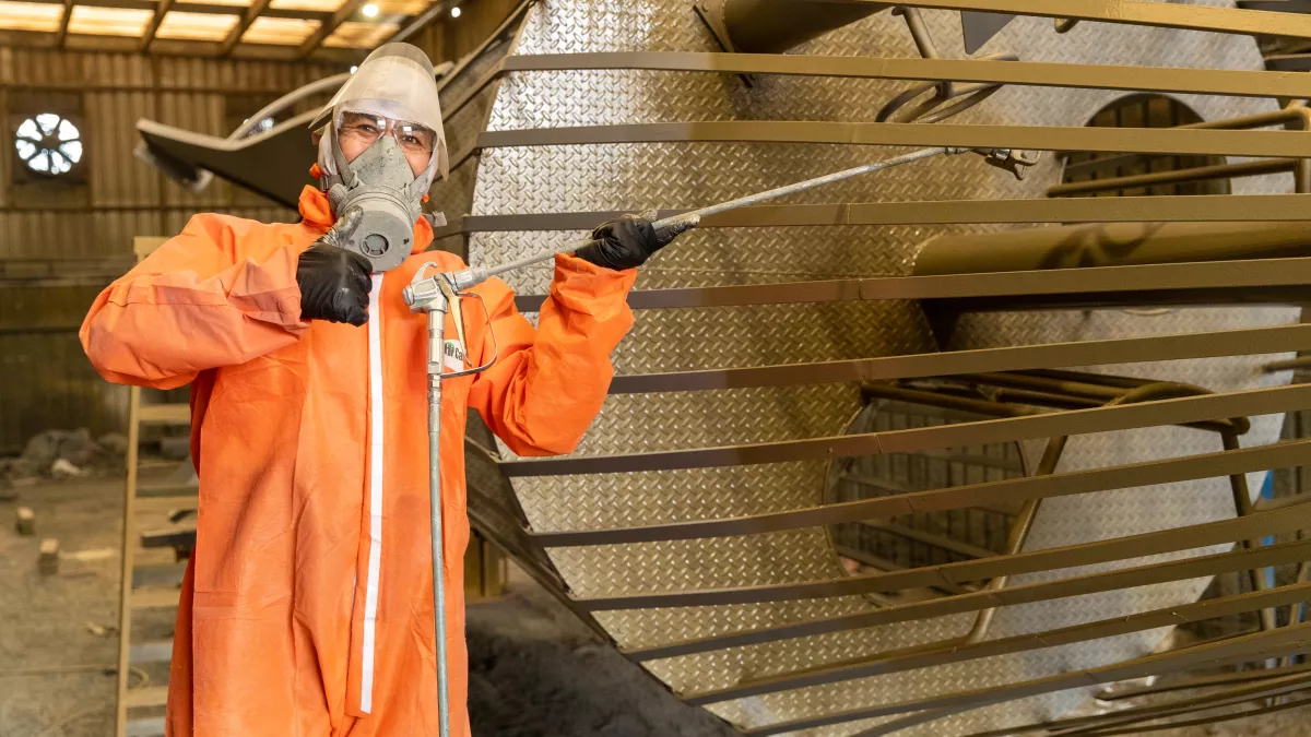 A person wearing a bright orange safety jumpsuit giving a thumbs up to the camera