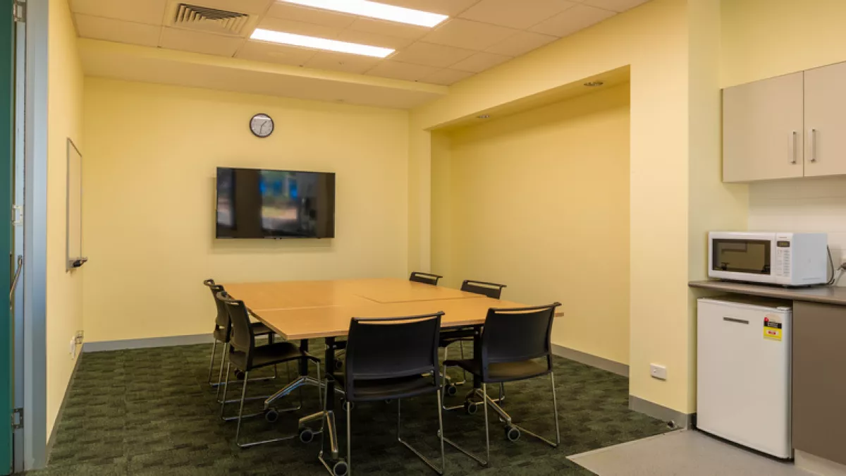 A small meeting room with TV and kitchenette