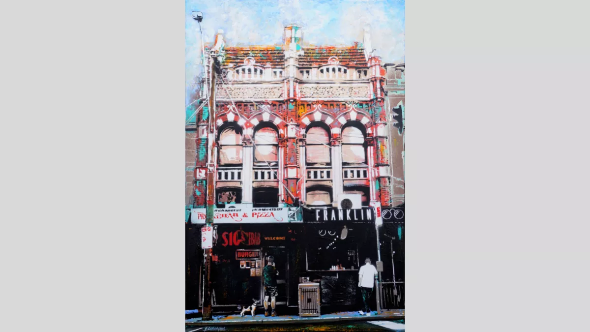 Building with two shopfronts and two people and a dog on footpath