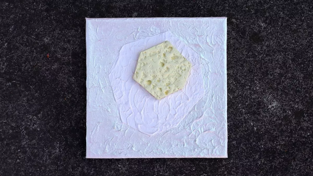A ceramic artwork of a cream coloured hexagon on a pale background