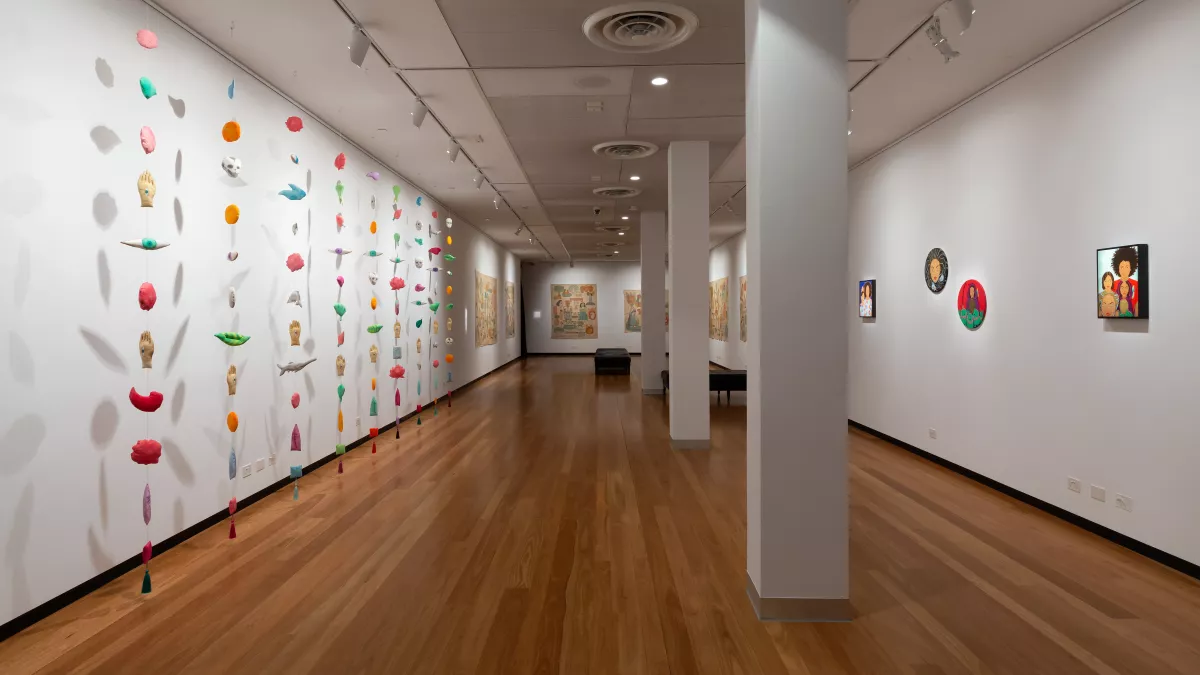 brightly coloured objects suspended on wire from a gallery ceiling