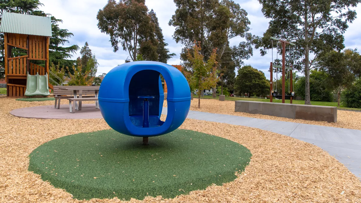 Playground showing blueberry spinner in foreground and other play equipment in background including timber unit and swings