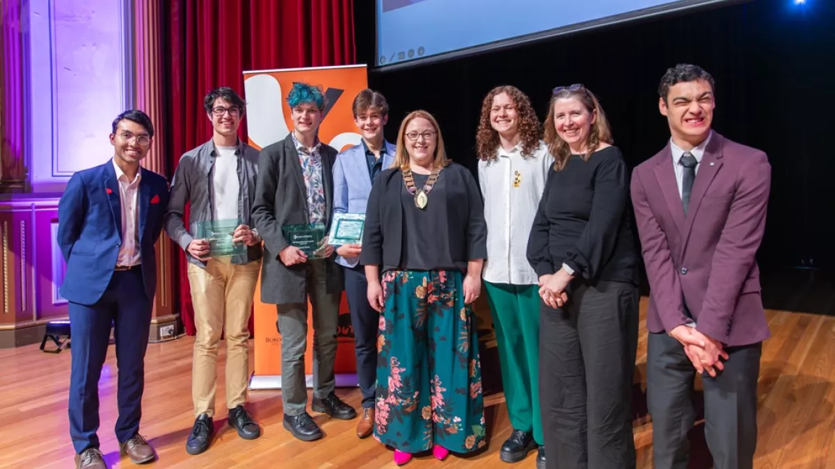 A group of young people standing with the Mayor, holding their winners plaques