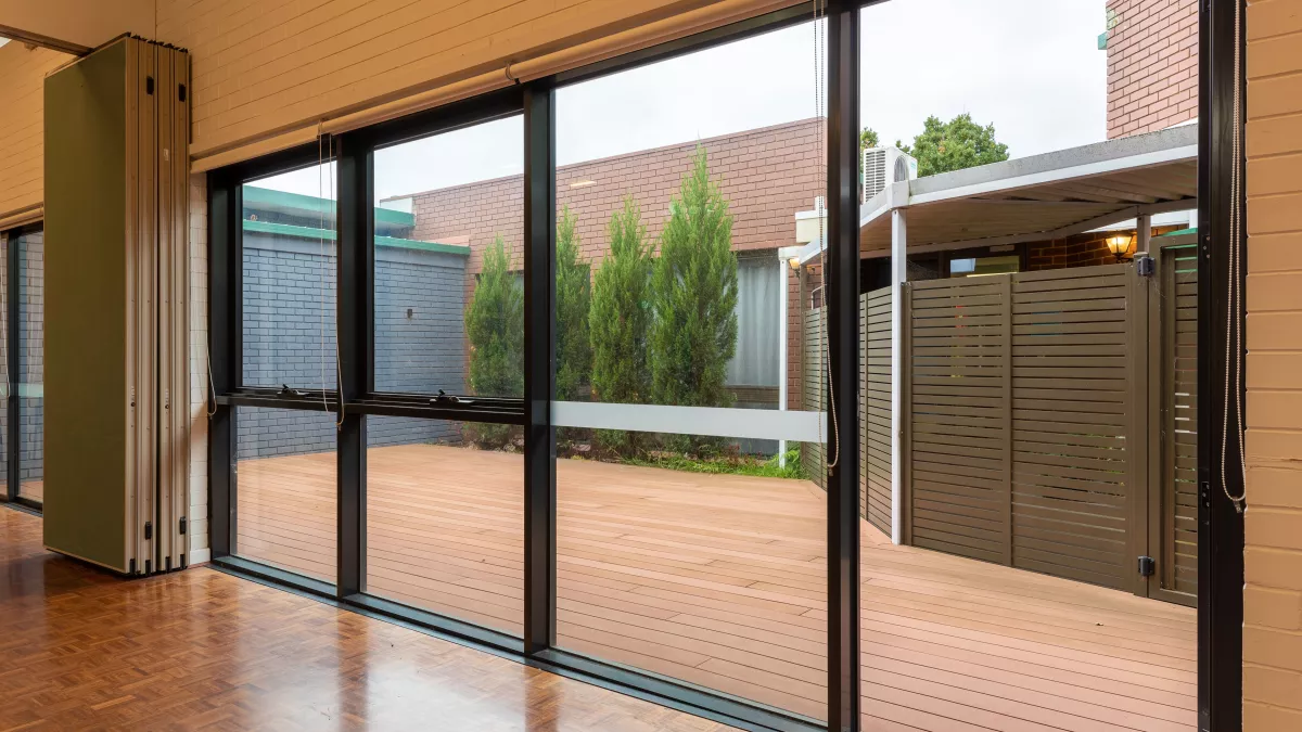 A small outdoor patio area surrounded by a brick wall, trees and a wooden fence