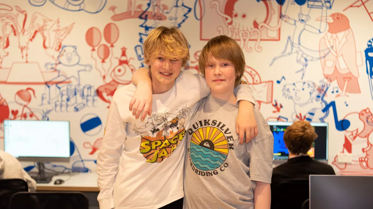 2 kids stand with arms around each other's shoulders