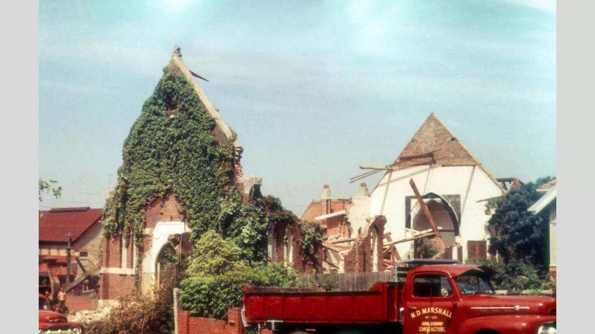 A partially demolished old church with ivy-covered walls. The building's structure is visibly deteriorated with exposed wooden beams and bricks. A red truck labeled 'N.D. Marshall' is parked in front, surrounded by rubble.