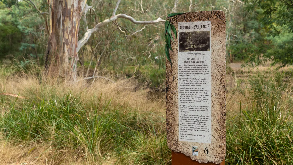 A trail maker with descriptive text along a grassy path in bushland