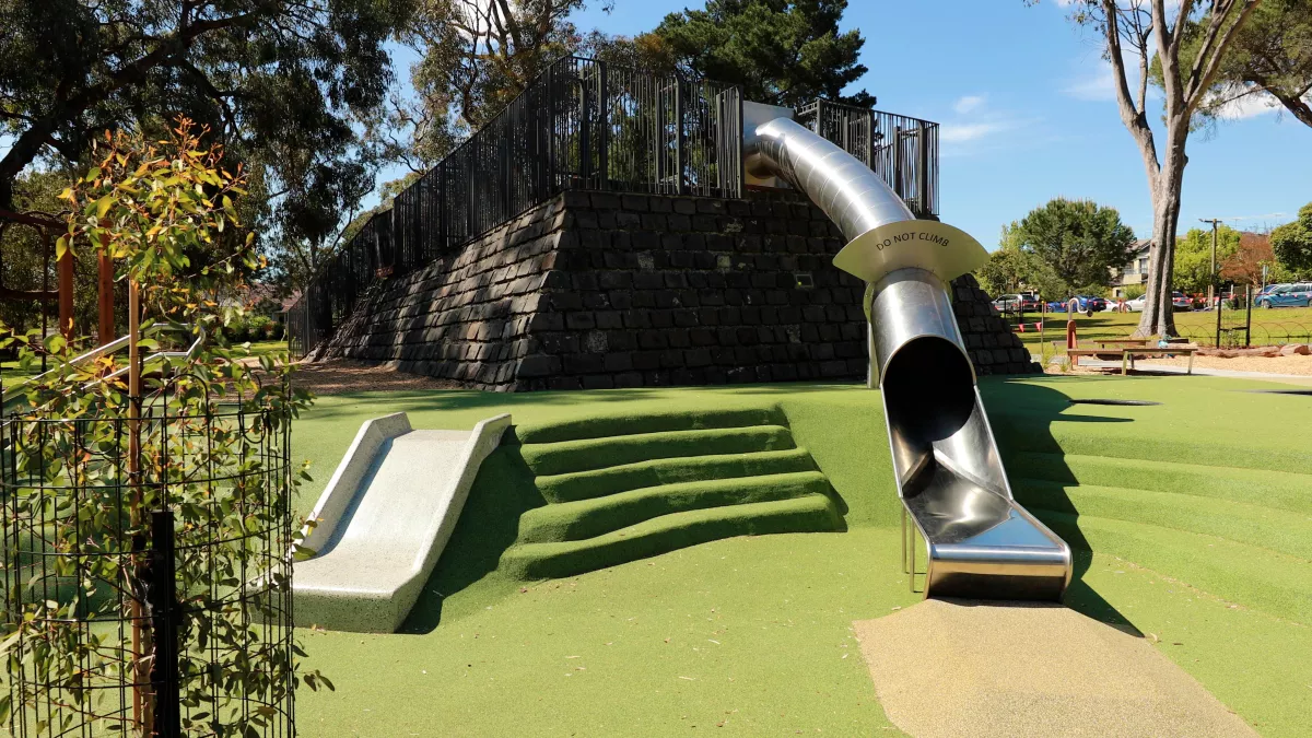 an enclosed slide and an open slide on fake grass