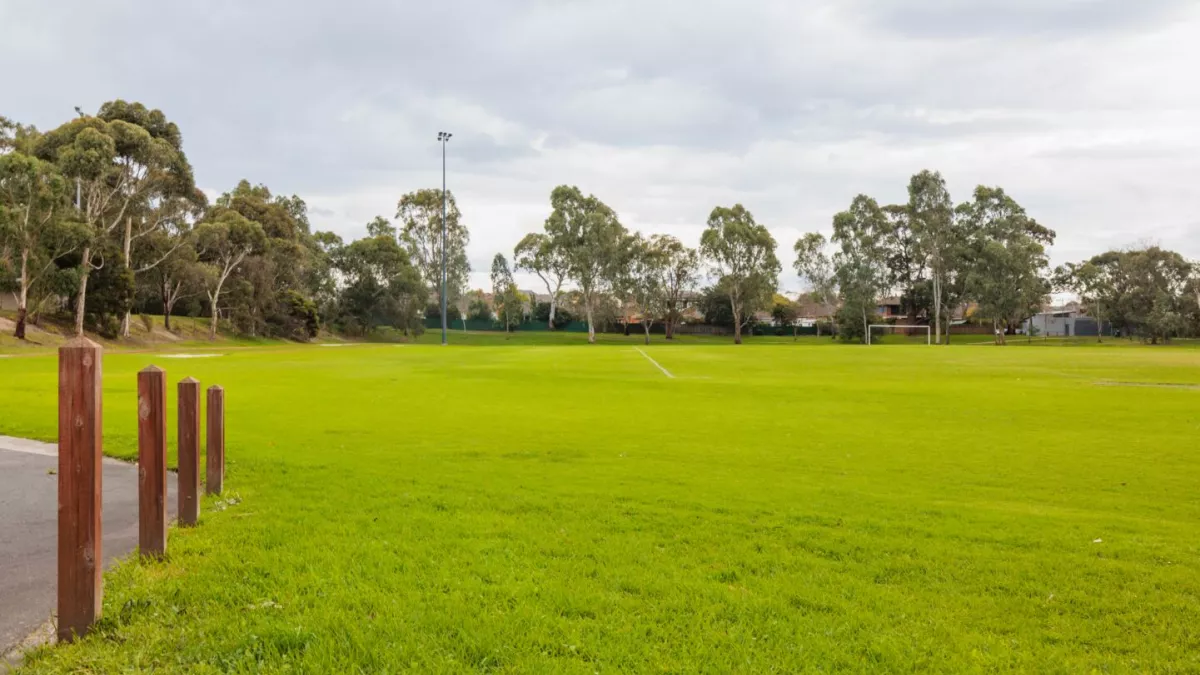 A green sportsground. Trees line the edge of the grassed area.
