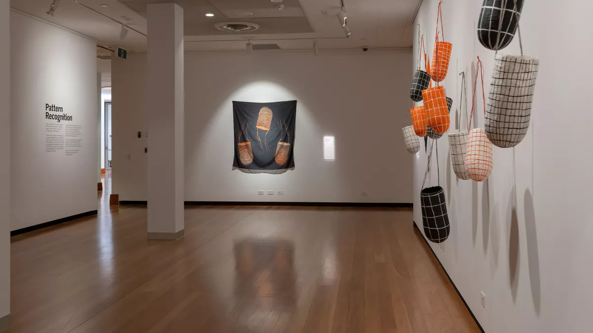 Photo of hanging paper sculptures and silk hanging in a gallery. 