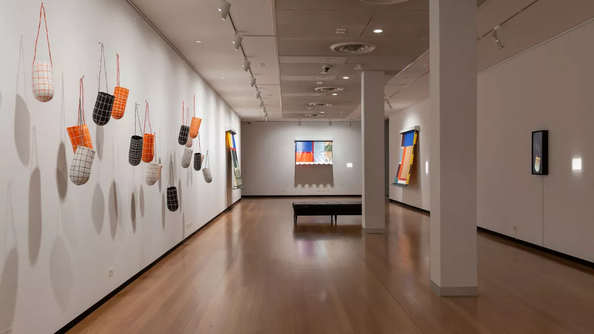 Photo of hanging paper sculptures and mixed media work in a gallery. 