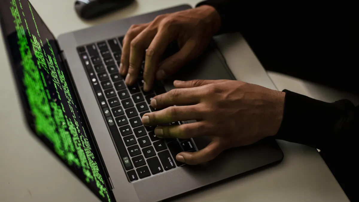 A persons hands typing on a laptop