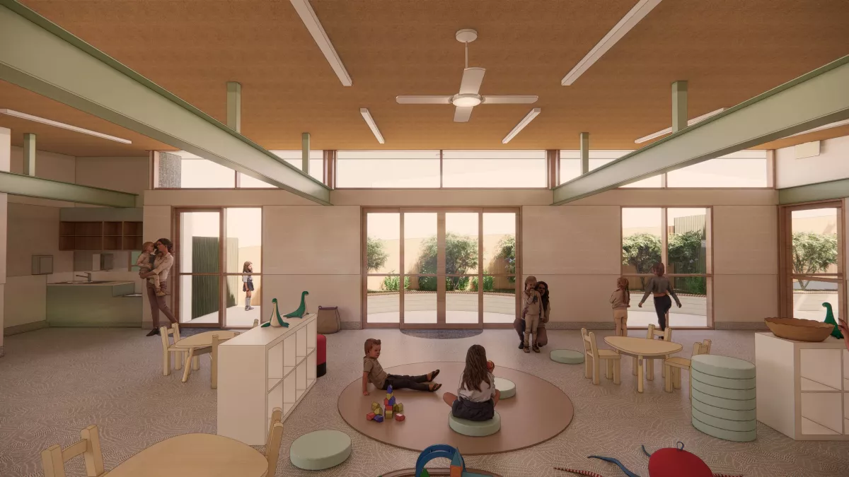 a kindergarten room withchildren's chairs and tables, storage cubes and toys. Children are sitting around the room