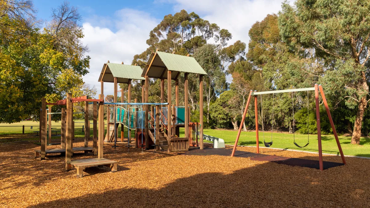 a playground with swings and shaded climbing area