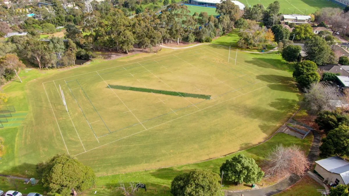 A large grassy sports oval surrounded by trees