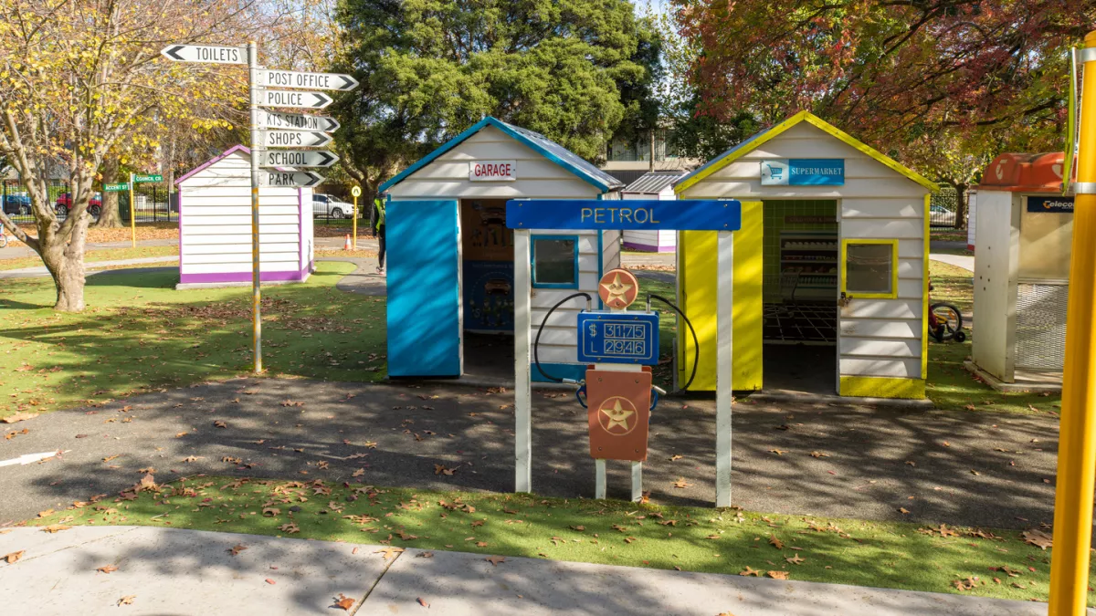 A petrol bowser in front of a garage and a supermarket