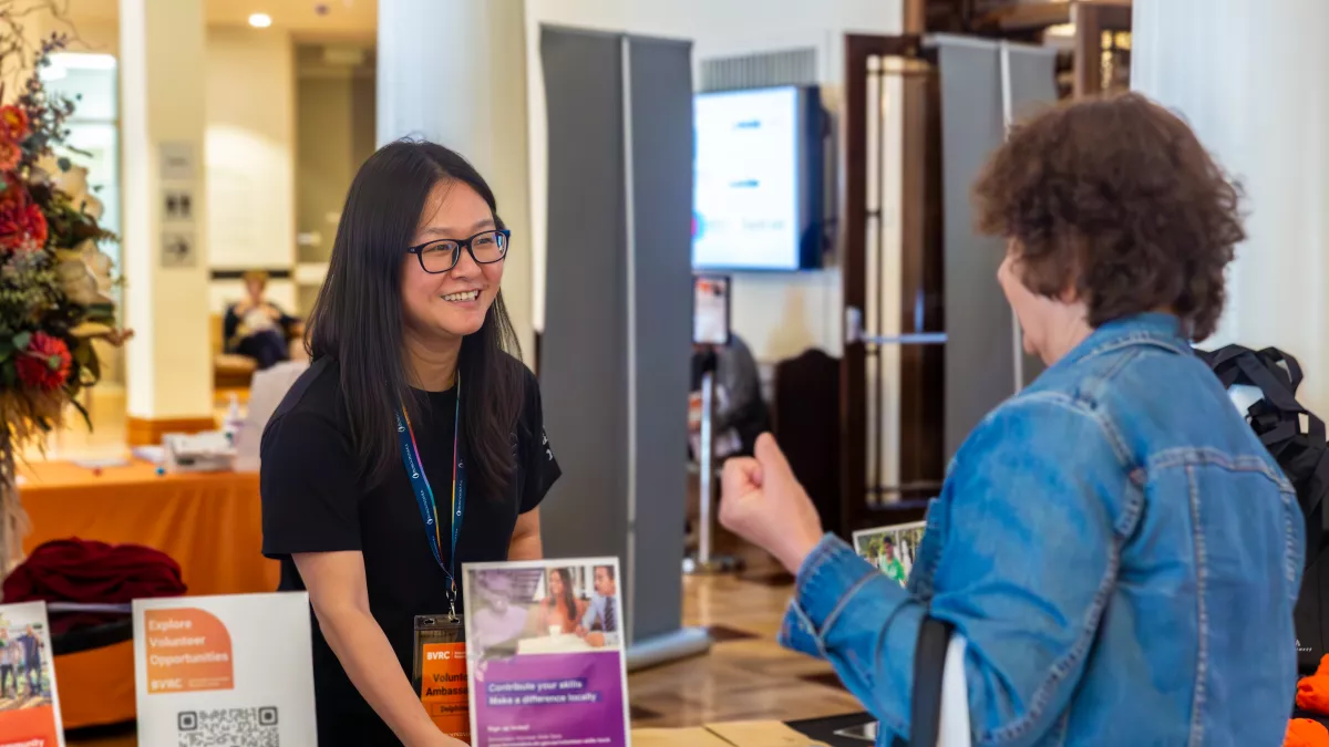 2 women talk to each other over a community stall