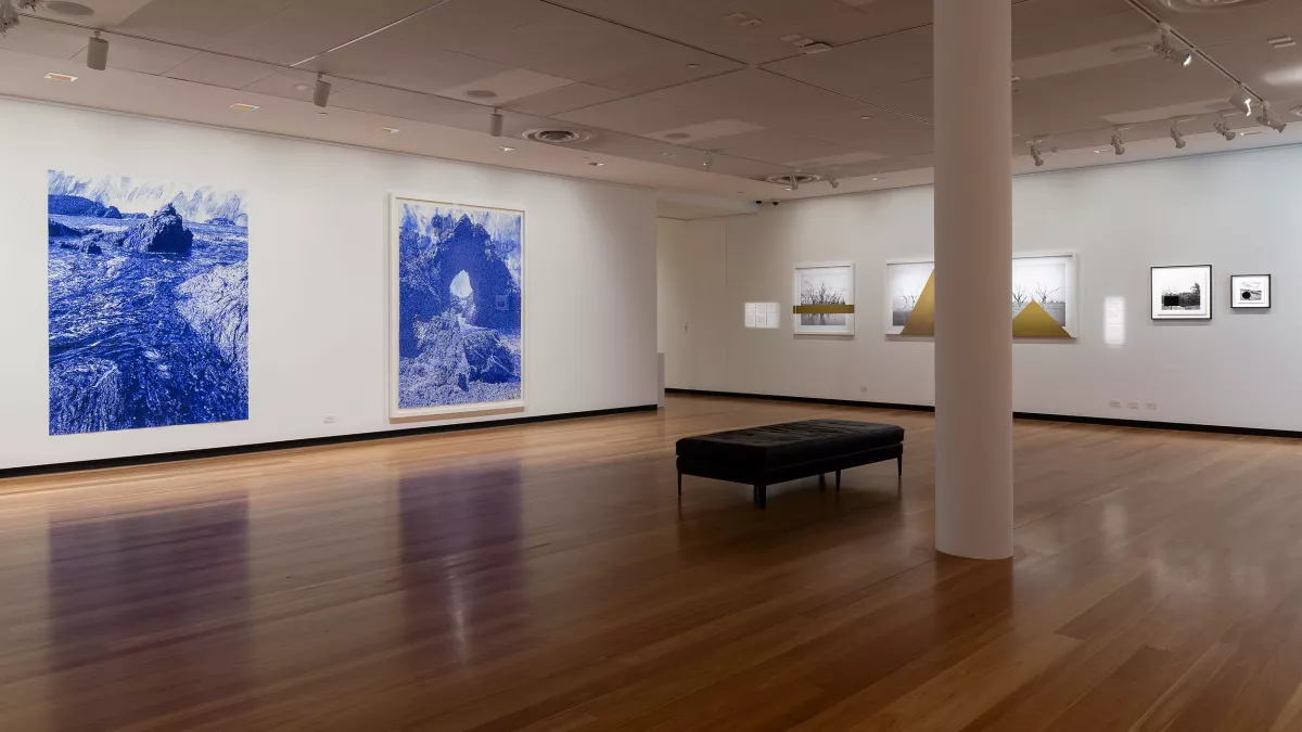 A spacious gallery features large-scale blue and white landscape prints alongside framed black and white photography with gold geometric elements.