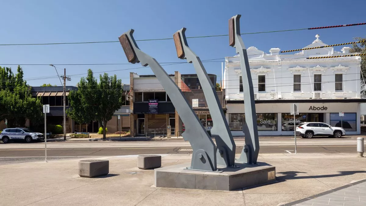 a view from the back of a large sculpture. The sculpture features three arms that mimic the arms of a typewriter