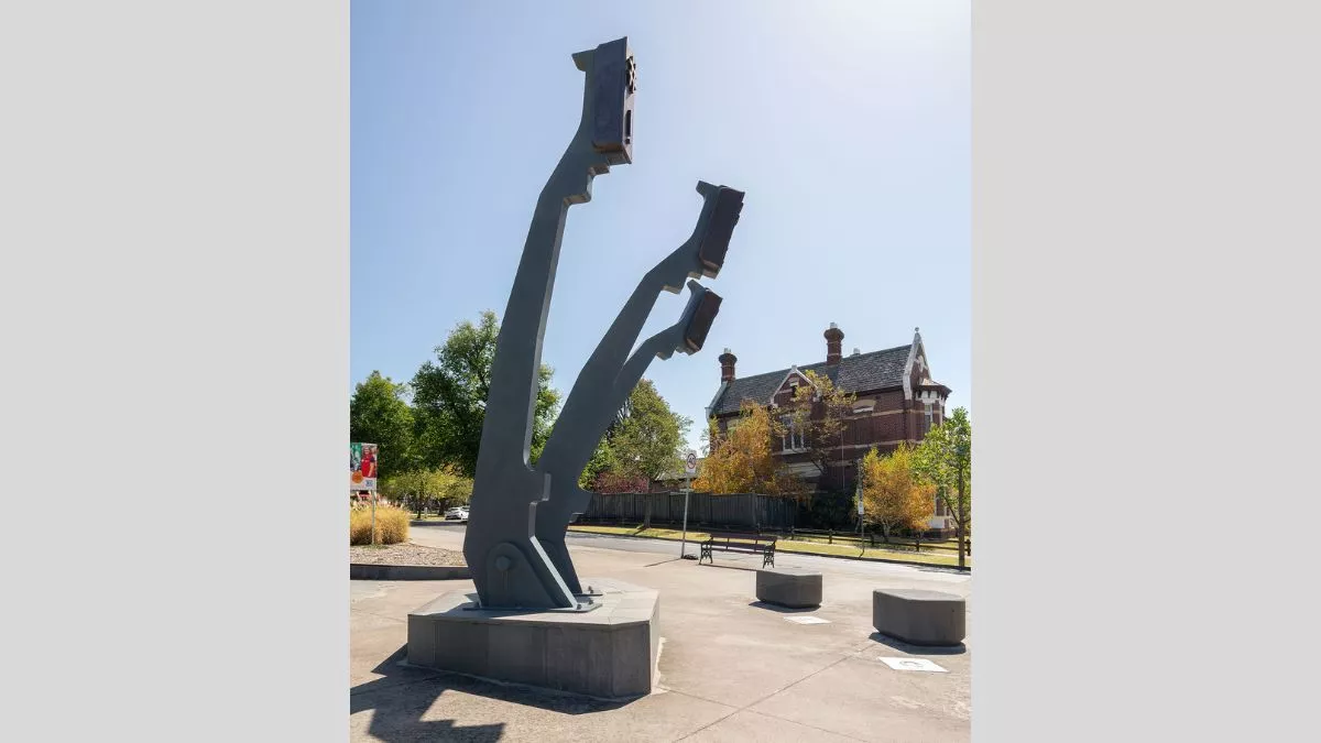 a view from the side of a large sculpture. The sculpture features three arms that mimic the arms of a typewriter