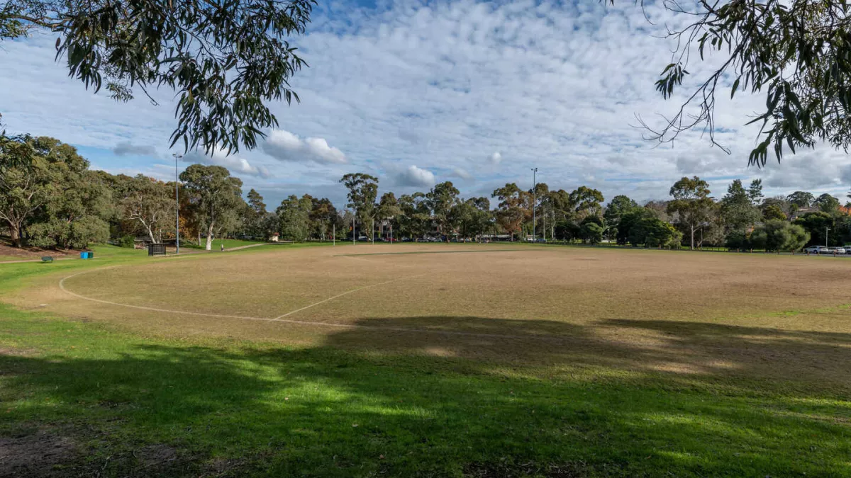 An oval with line markings and brown grass with AFL goal posts on the far side