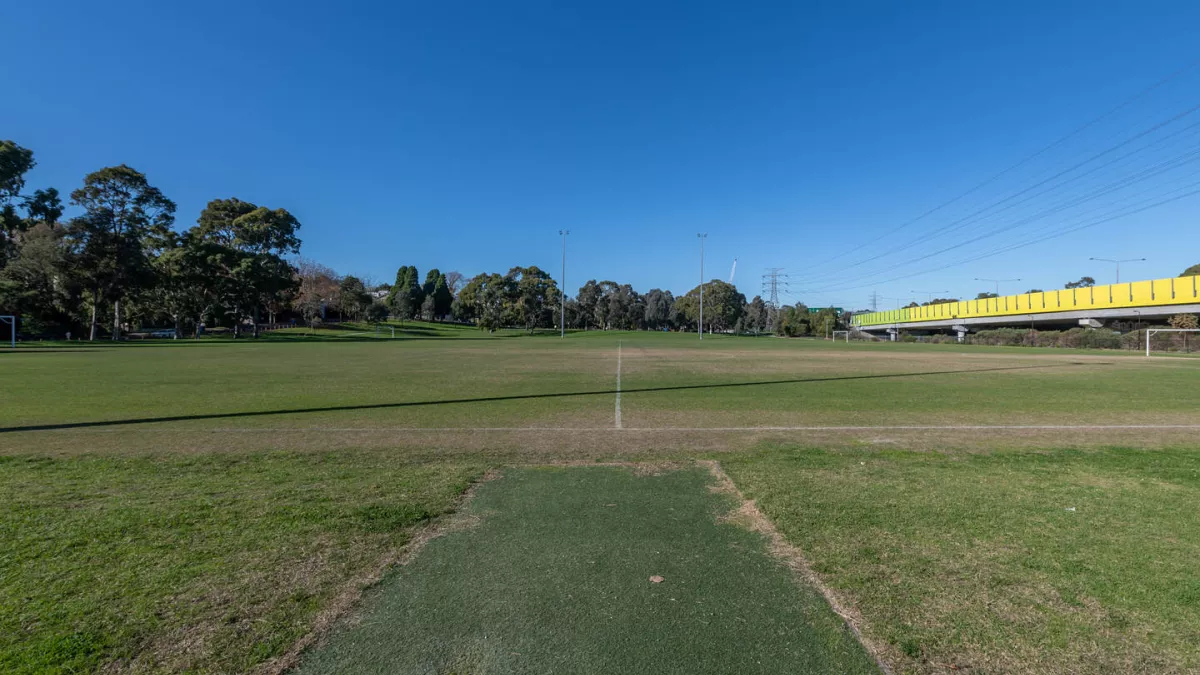 A sportsground with a close up view of a synthetic cricket pitch