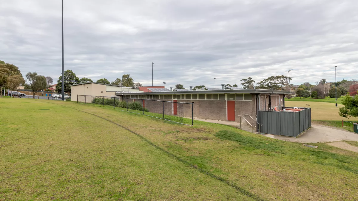 The edge of a sportsground oval looking forwards a small building