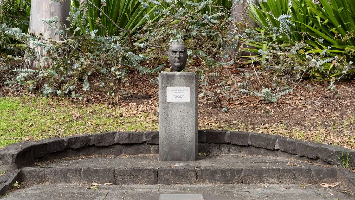 A small bronze head of a man with short hair. The head is attached to a rectangular column