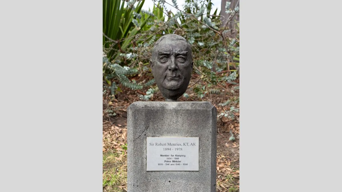 A small bronze head of a man with short hair. The head is attached to a rectangular column