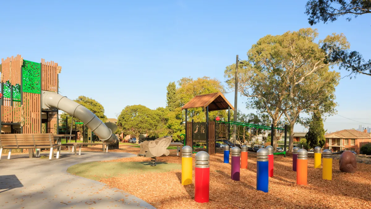 a playground ringed by trees in soft light