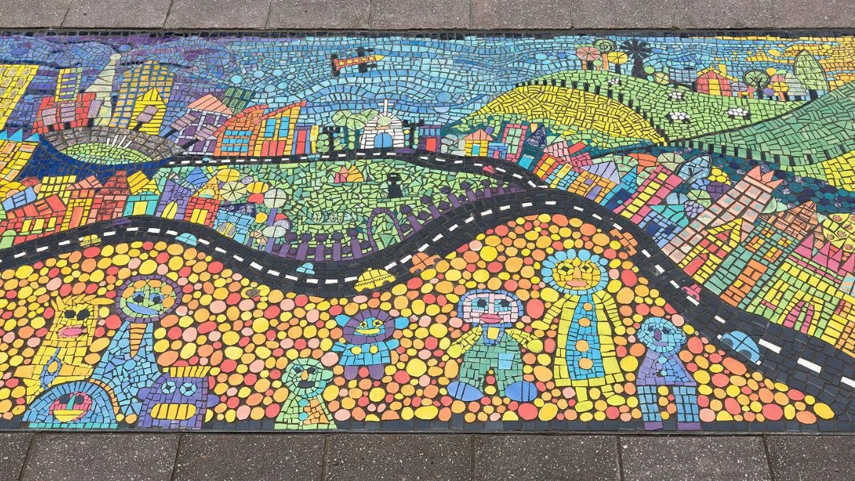 A colourful mosaic featuring smiling people, buildings and green hills