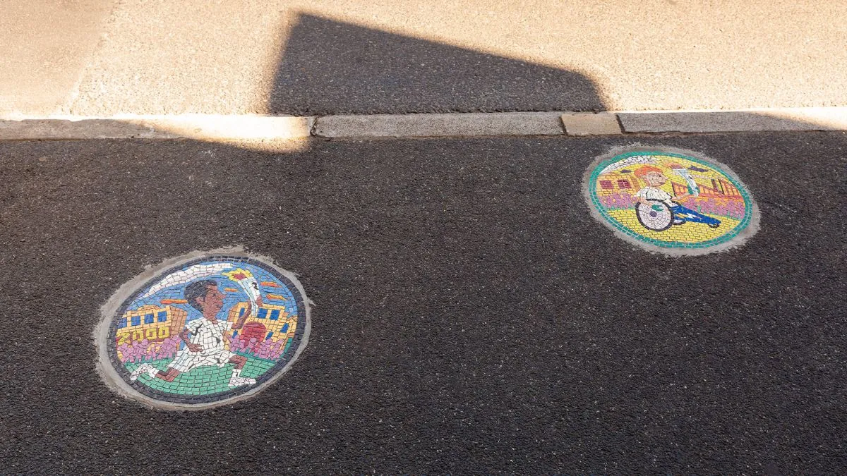 Two small, round tile mosaics embedded in a footpath
