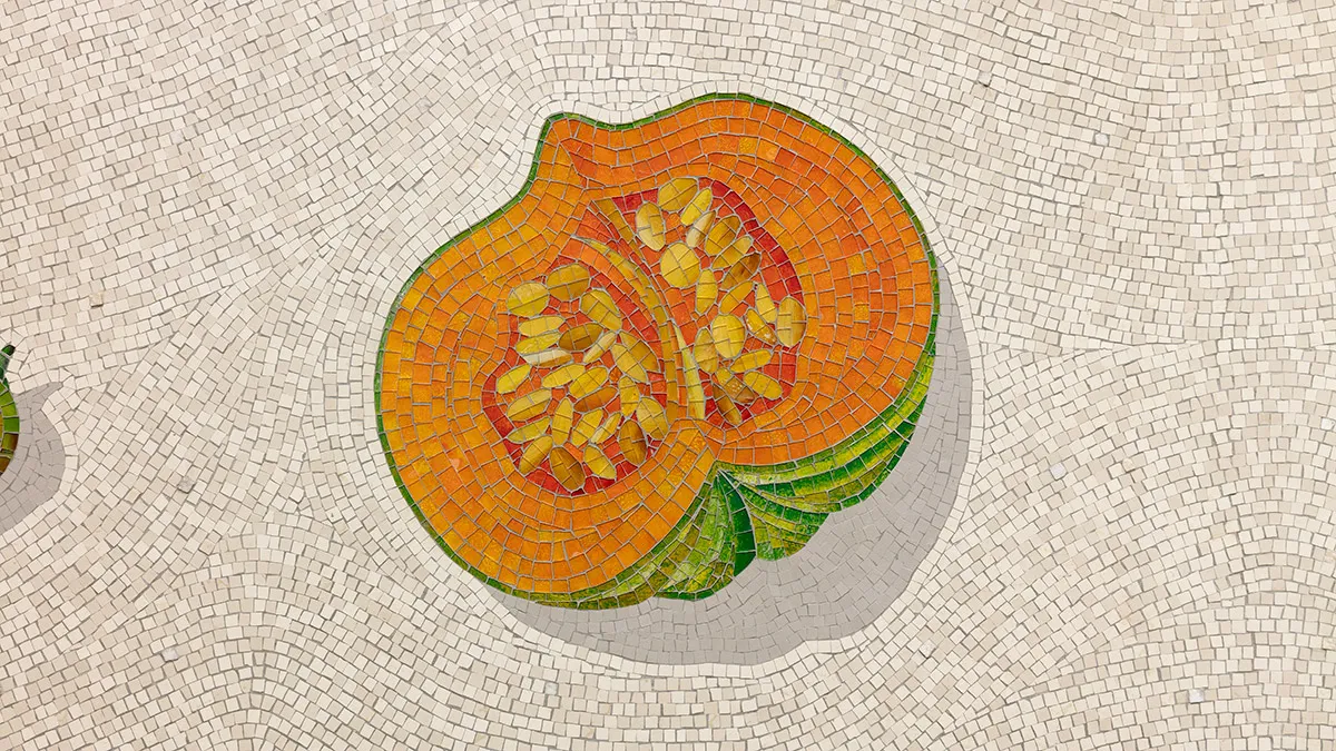A close up photograph of a mosaic of a pumpkin on a white background