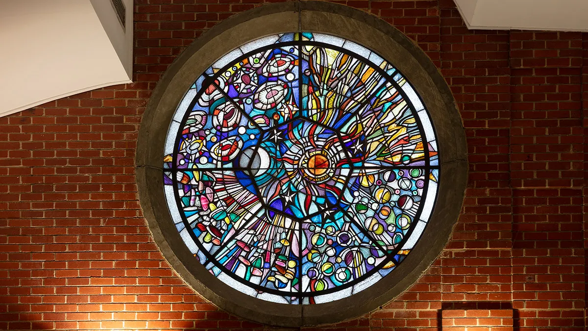 A circular stained glass window mounted into a brick wall