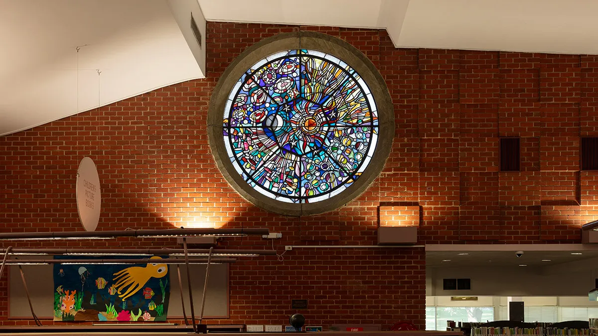 A circular stained glass window mounted high up in a brick wall