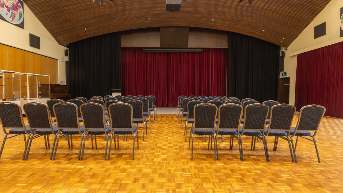 Rows of seats facing towards a stage-like area with red curtains.